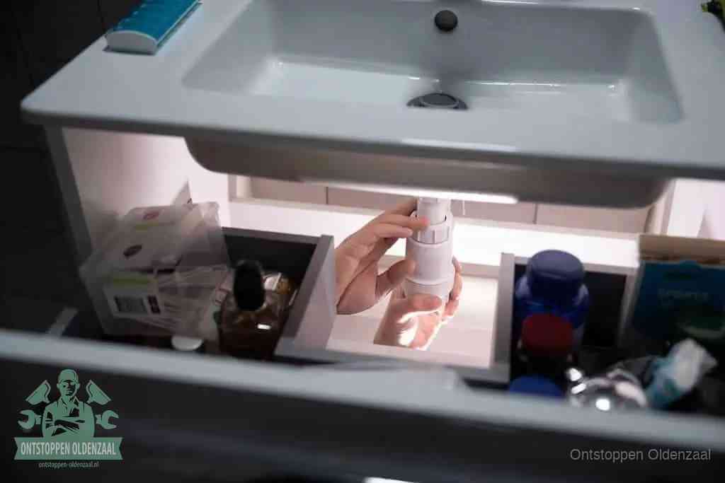 Een pompfles met zeep boven een wastafel, de heet water en afwasmiddel-methode om een vetprop in de afvoer los te maken in Oldenzaal