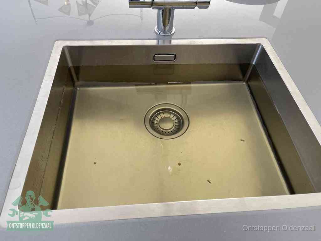Stilstaand water in een rvs spoelbak dat niet wegloopt, een duidelijk signaal van een gootsteenverstopping in Oldenzaal