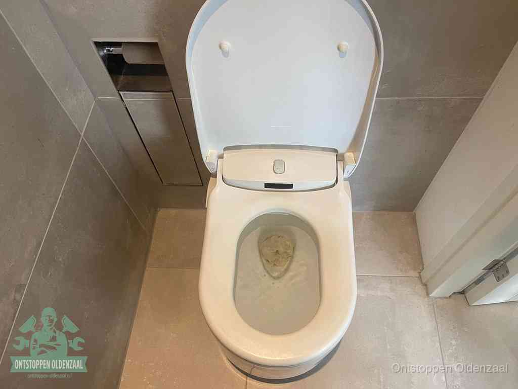 Een wit hangtoilet waarin een prop wc-papier op het water blijft drijven, een duidelijk signaal van een verstopte wc in Oldenzaal
