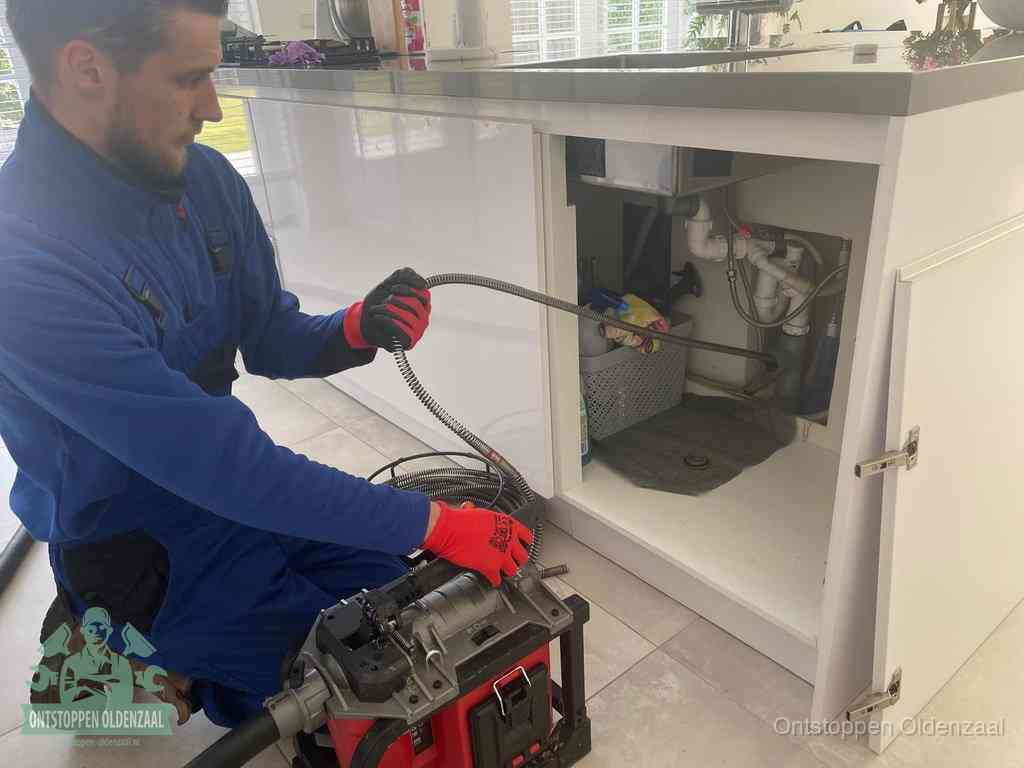 Een monteur reinigt de keukenafvoer grondig met een veermachine om terugkerende gootsteenverstoppingen te voorkomen in Oldenzaal