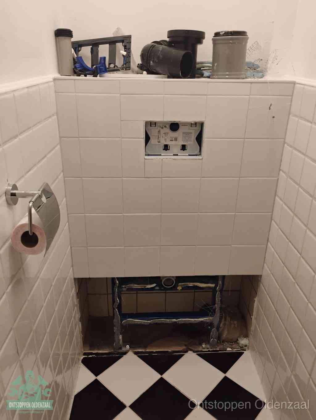Een toiletruimte waar het hangtoilet en de inbouwreservoir-onderdelen zijn vrijgelegd voor onderhoud, periodiek nazicht voorkomt een wc-verstopping in Oldenzaal